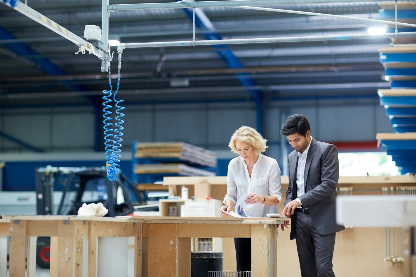 A businessman and a businesswoman check the paperwork of their manufacturing site in India.